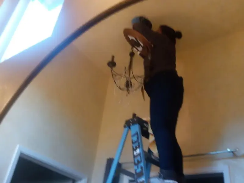 Electrician installing a chandelier in a Pima residence
